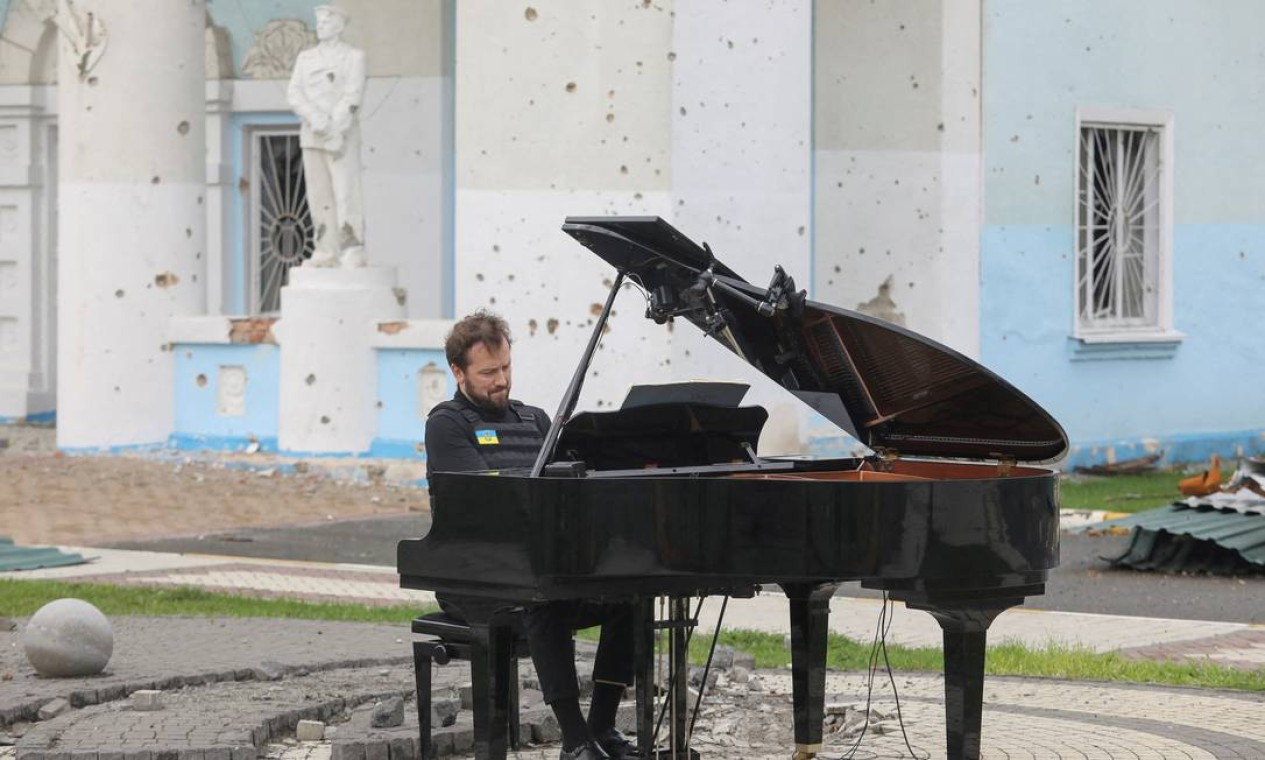 Músico lituano Darius Mazintas toca piano em frente à Casa Central da Cultura destruída durante a invasão da Rússia, na cidade de Irpin, nos arredores de Kiev Foto: STRINGER / REUTERS