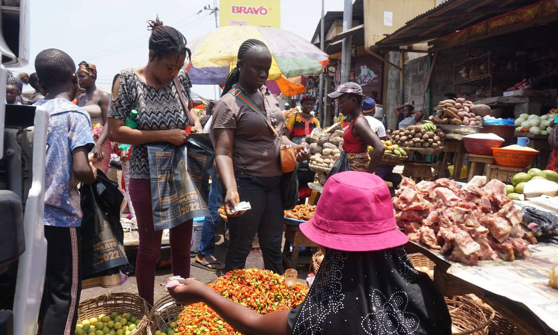 Uma mulher compra comida em um mercado em Freetown, capital da Serra Leoa, onde os preços dos produtos básicos aumentaram desde a pandemia da Covid e a invasão da Ucrânia pela Rússia Foto: Saidu Bah / AFP / 6-4-2022