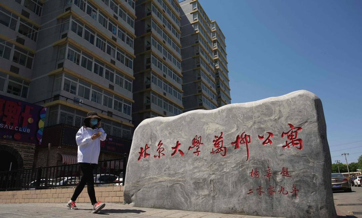 Mulher caminha perto de uma entrada do campus Wanliu da Universidade de Pequim depois que centenas de estudantes protestaram contra restrições para conter a propagação da Covid-19 Foto: NOEL CELIS / AFP