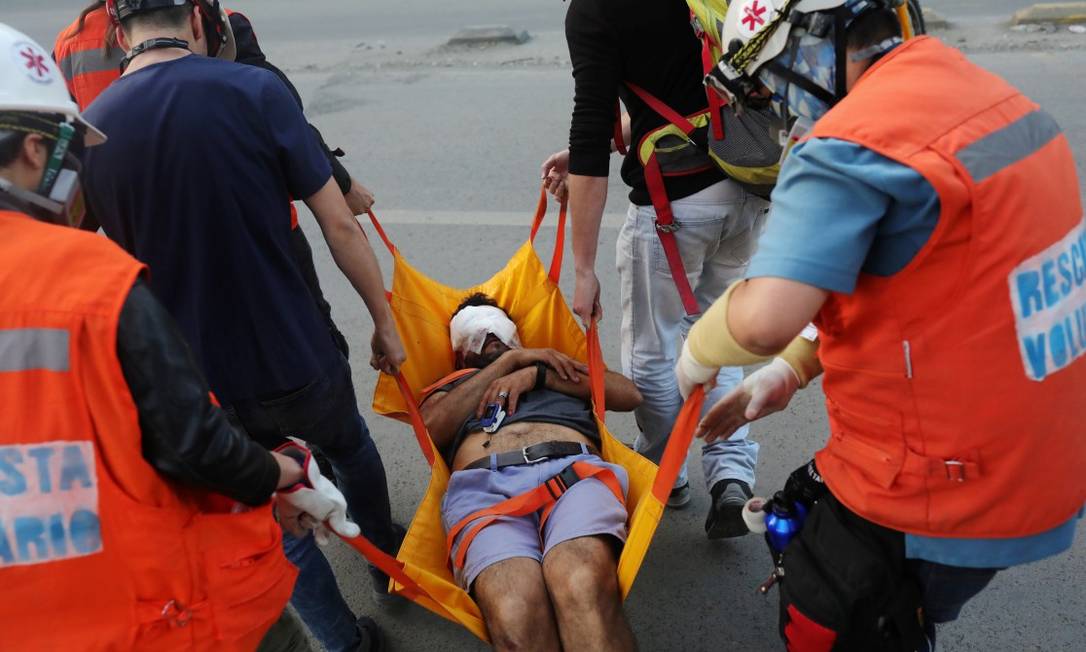 Um manifestante atingido no rosto pela polícia chilena recebe assistência médica em Santiago Foto: PABLO SANHUEZA / REUTERS