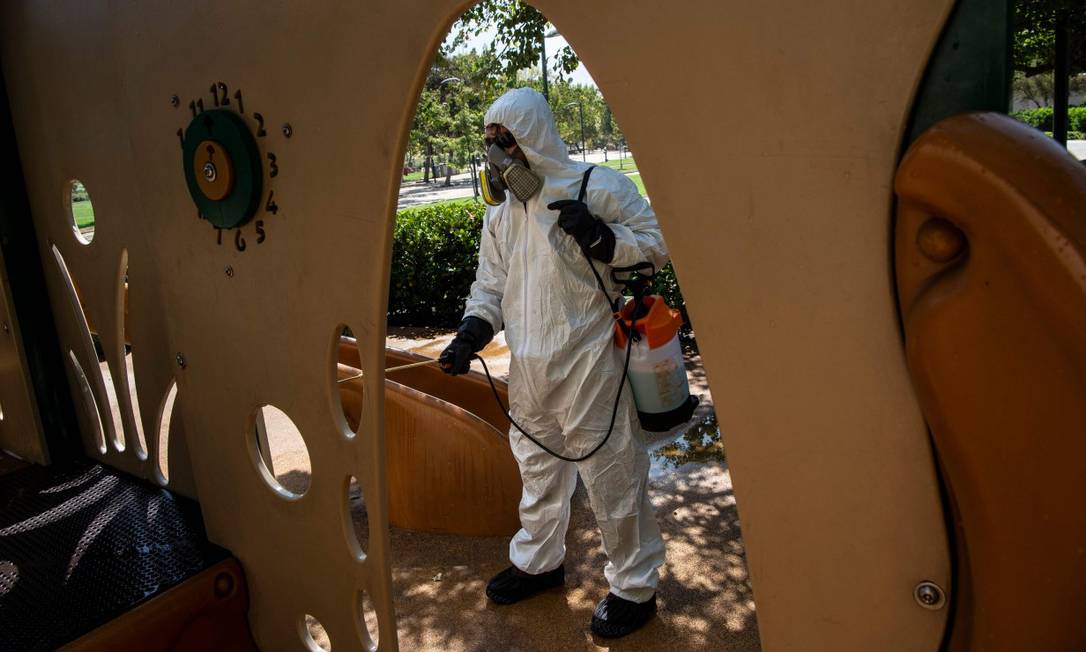 Trabalhador da saúde desinfeta parque infantil em Santiago Foto: MARTIN BERNETTI / AFP