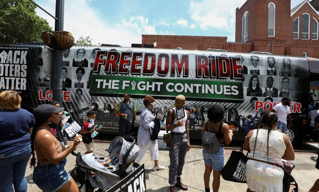 Pessoas se reúnem em frente a veículos que fazem campanha por direitos eleitorais em Atlanta, na Geórgia Foto: DUSTIN CHAMBERS / REUTERS