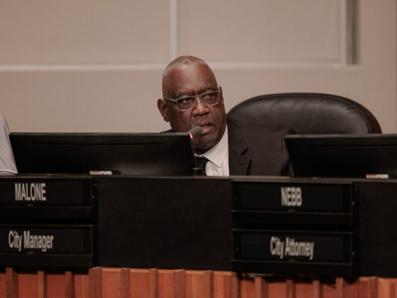 Vallejo City Manager Michael Malone, who is a Black man in his 60s, speaks from a city council dais while wearing a dark suit, white shirt and dark tie.