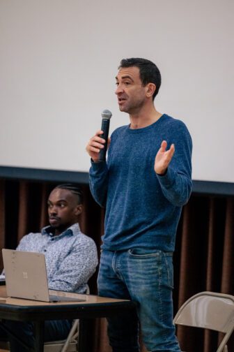 ACLU attorney Avi Frey speaks while holding a microphone as his colleague Marshal Arnwine looks on.