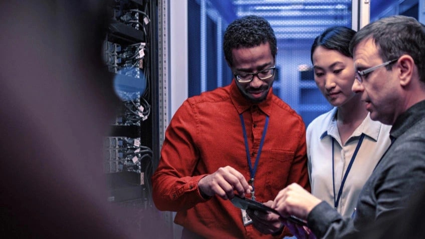 Three IT professionals collaborating over a tablet