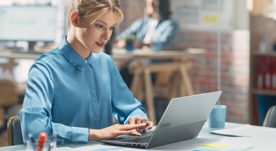 Women in a blue shirt working in an open case ThinkBook 14 Gen 6 Intel (14″).