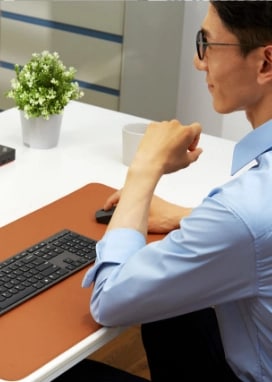 A man in a business casual outfit smiles as he looks at a Lenovo ThinkVision monitor.