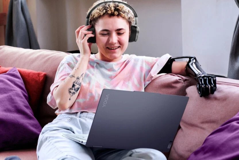 A young person with a prosthetic hand using a Lenovo Yoga laptop.