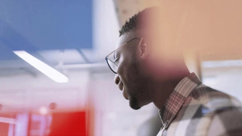 A closeup of an African-American man wearing glasses and looking to his right