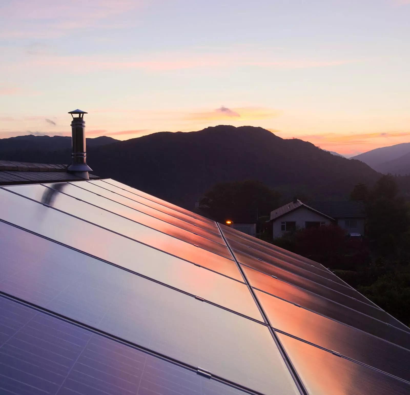 House with solar panels on the roof in a rural mountain setting.