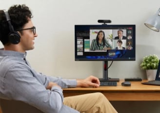 A casually dressed businessman is content as he sits as his desk and speaks to Lenovo Pro support virtually on his ThinkVision monitor.