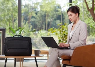 A well-dressed businesswoman reading content using a Lenovo ThinkPad X1 Carbon in her brightly lit office.