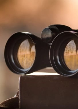 A vintage set of binoculars sitting on a book.