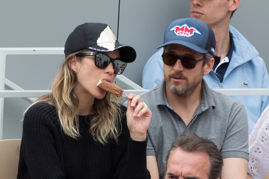 Marion Cotillard munches on an ice cream bar while watching the French Open with her husband Guillaume Canet.