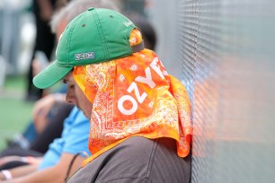 a person sits with a baseball cap and an OZY Fest bandana