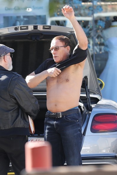 Jean-Claude Van Damme shows off his muscular physique, switching his shirt while talking to a friend next to his Bentley convertible.