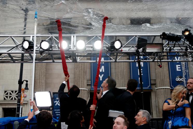 Staff clears rain water from above the Oscars 2020 red carpet.