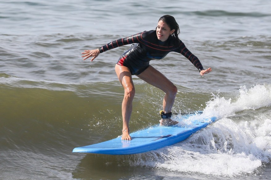 Bethenny Frankel rides a wave in the Hamptons while taking a beach break with boyfriend Paul Bernon.