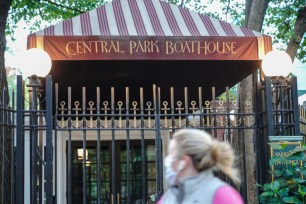 A woman wearing a face mask walks past the Central Park's historic Loeb Boathouse restaurant