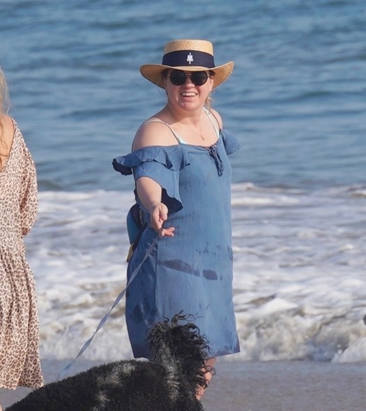 Kelly Clarkson smiles on the beach with her dog.