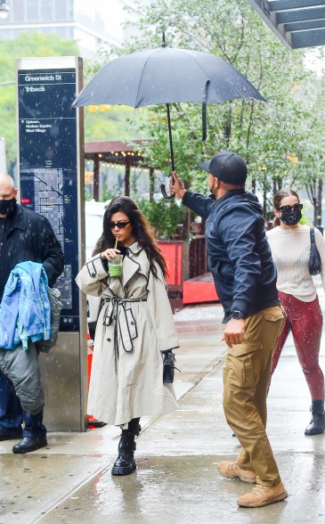 Kourtney Kardashian gets the star treatment as she sips on a juice while her assistant protects her from the rain.