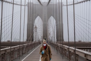 A woman wearing a mask walks the Brooklyn Bridge in March 2020