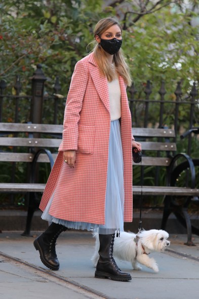 Olivia Palermo keeps warm in a pink patterned coat while walking her dog in New York City.