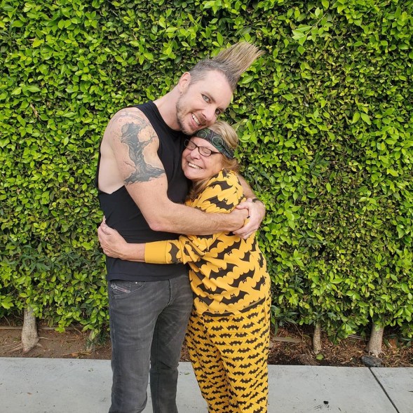 Dax Shepard dons a mohawk and eyeliner as he hugs his mom, who is dressed in Batman pajamas.