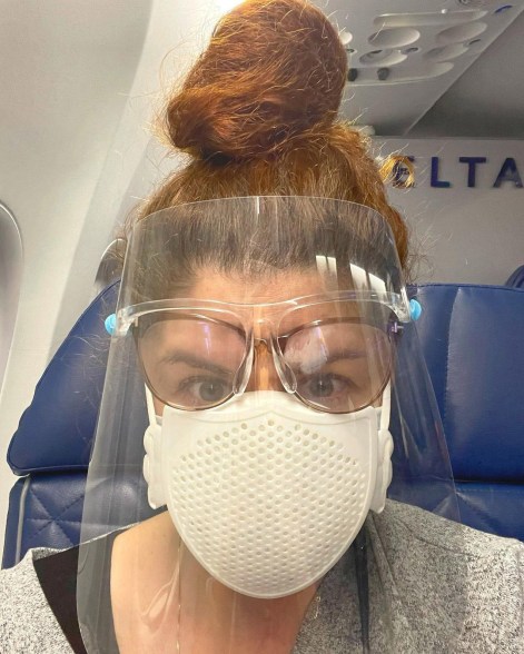 Debra Messing struggles with her glasses while wearing PPE on her flight.