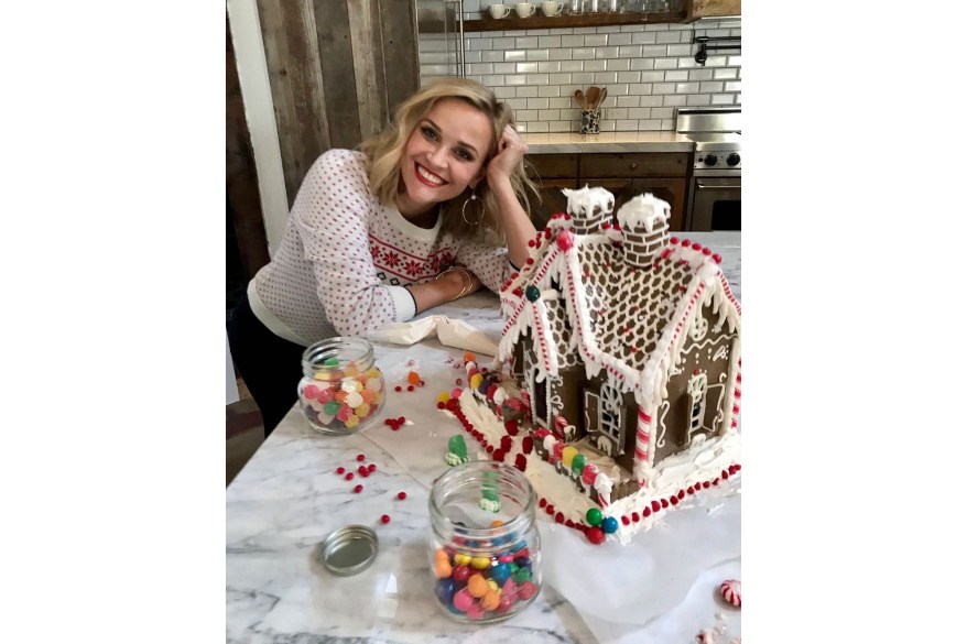 In Nashville, Reese Witherspoon smiles with a gingerbread house she and her kids decorated.