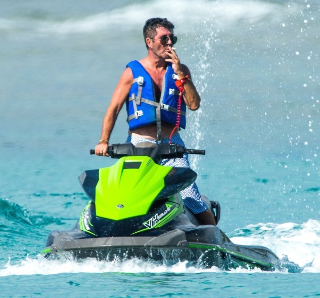 Four months after breaking his back in a scooter accident, Simon Cowell smokes a cigarette on a jet ski in Barbados.