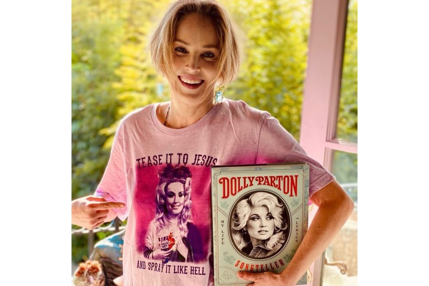 Sharon Stone shows off her Dolly Parton merch to honor the singer’s 75th birthday.