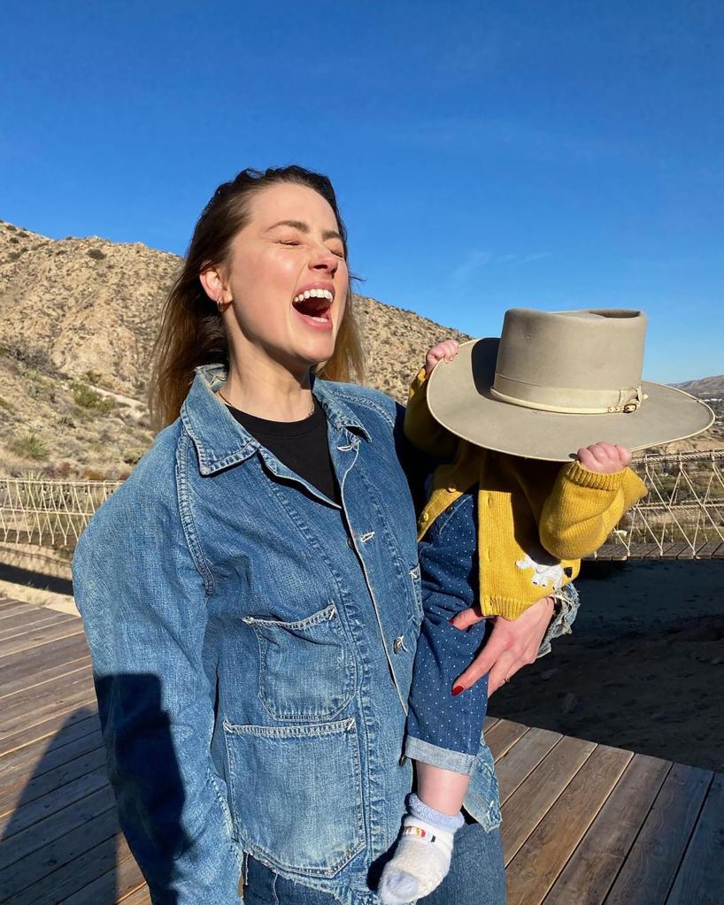 Amber Heard laughs in denim whole holding daughter Oonagh outside