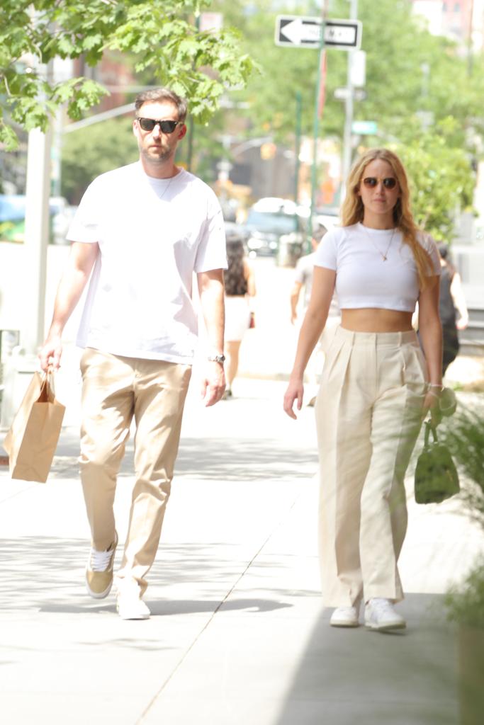 Cooke Maroney and Jennifer Lawrence walking in New York City in matching white T-shirts and tan pants.