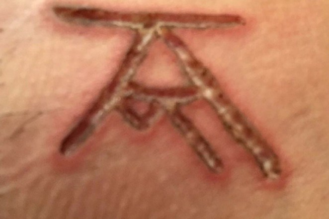 Members that Allison Mack recruited as "slave master" were branded with this mark, a combination her and Kieth Raniere's initials.