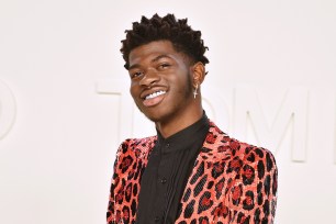 Lil Nas X poses on a red carpet.