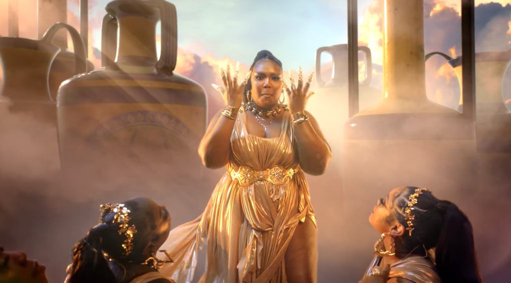 Lizzo wearing a gold dress in her "Rumors" music video