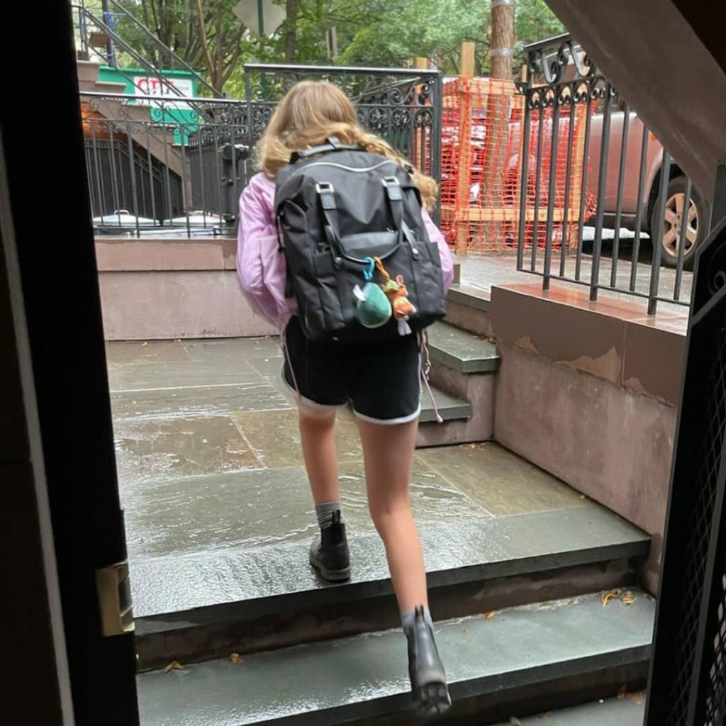 One of Sarah Jessica Parker's twin daughters walks to school with her back facing the camera.