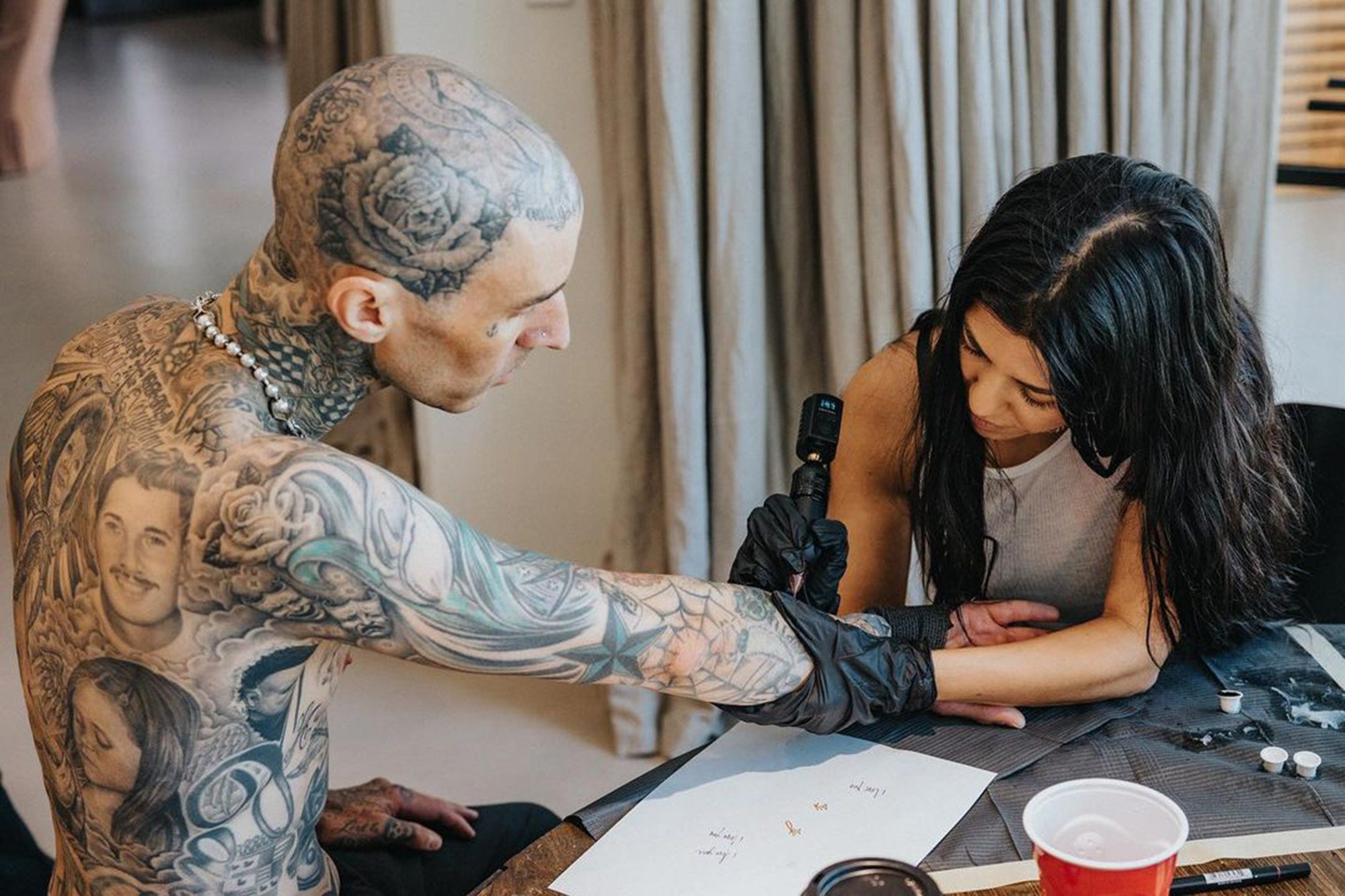 Kourtney Kardashian tattooing Travis Barker.