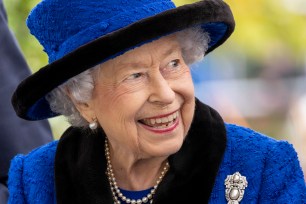 Queen Elizabeth II smiling and wearing a blue hat and jacket.