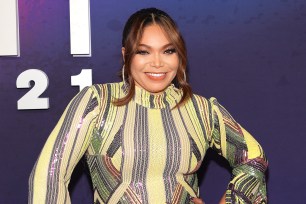 Tisha Campbell smiling and posing with her hands on her hips on the red carpet at the 2021 Soul Train Music Awards.