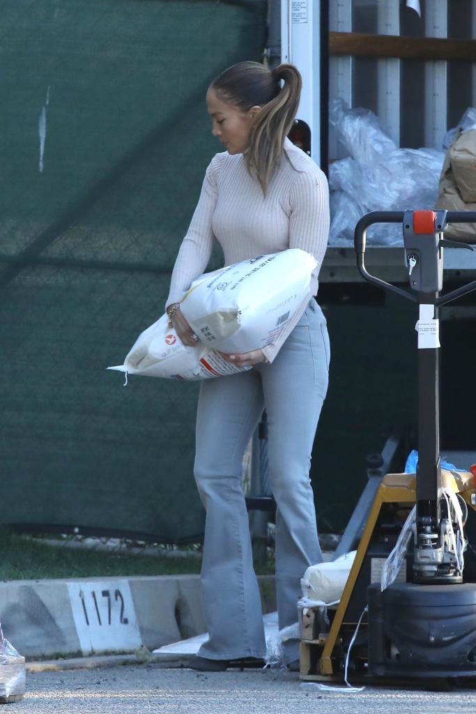 Lopez carrying a large bag of rice during Ben Affleck's holiday food drive.