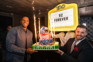 Michael Strahan holds a cake at his retirement jersey party