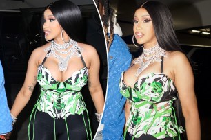 Cardi B in a black, white and green corset with a several diamond necklaces on