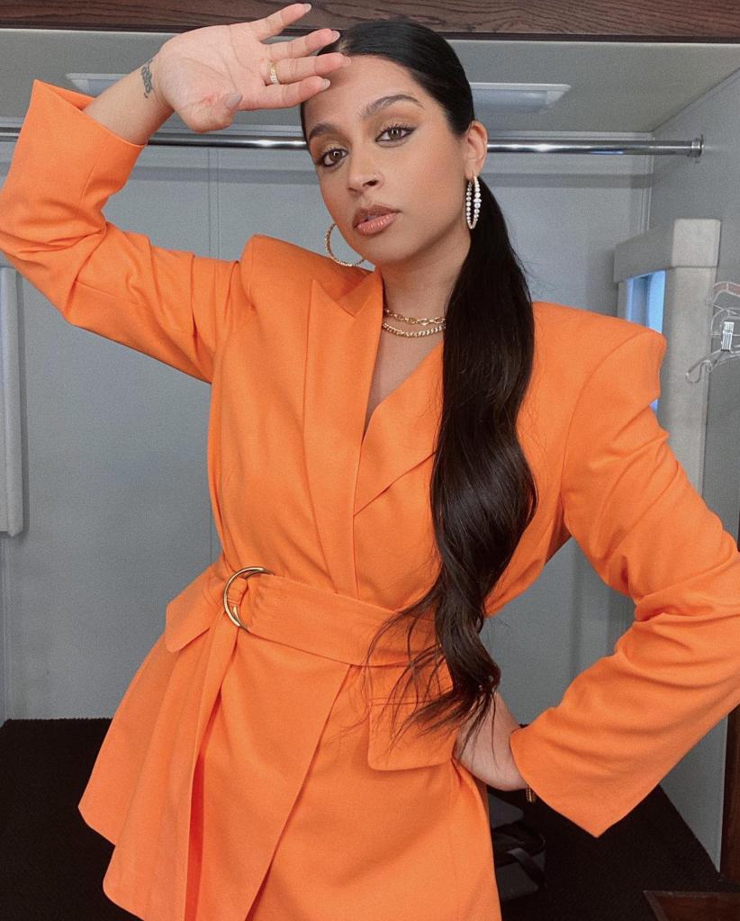 Lilly Singh posing in an orange suit.