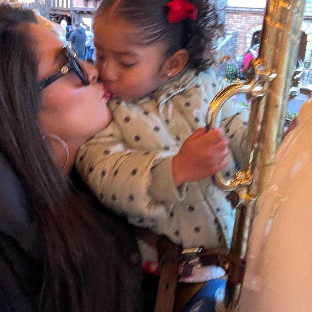 Vanessa Bryant giving daughter Capri a kiss on a carousel at Disneyland.