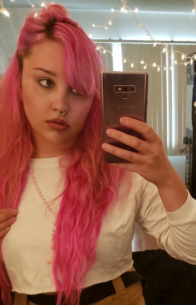 Amanda Bynes taking a mirror selfie with pink hair.