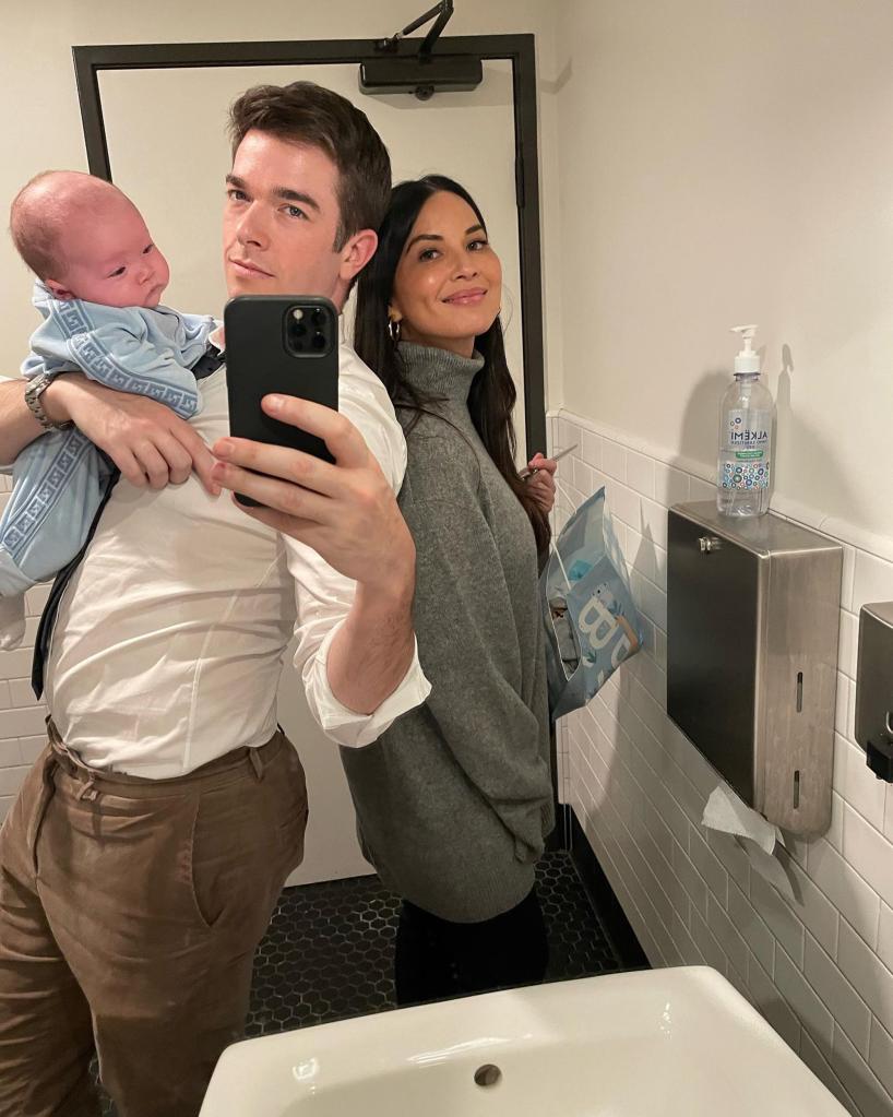 John Mulaney taking a mirror selfie with Olivia Munn while holding their son, Malcolm.