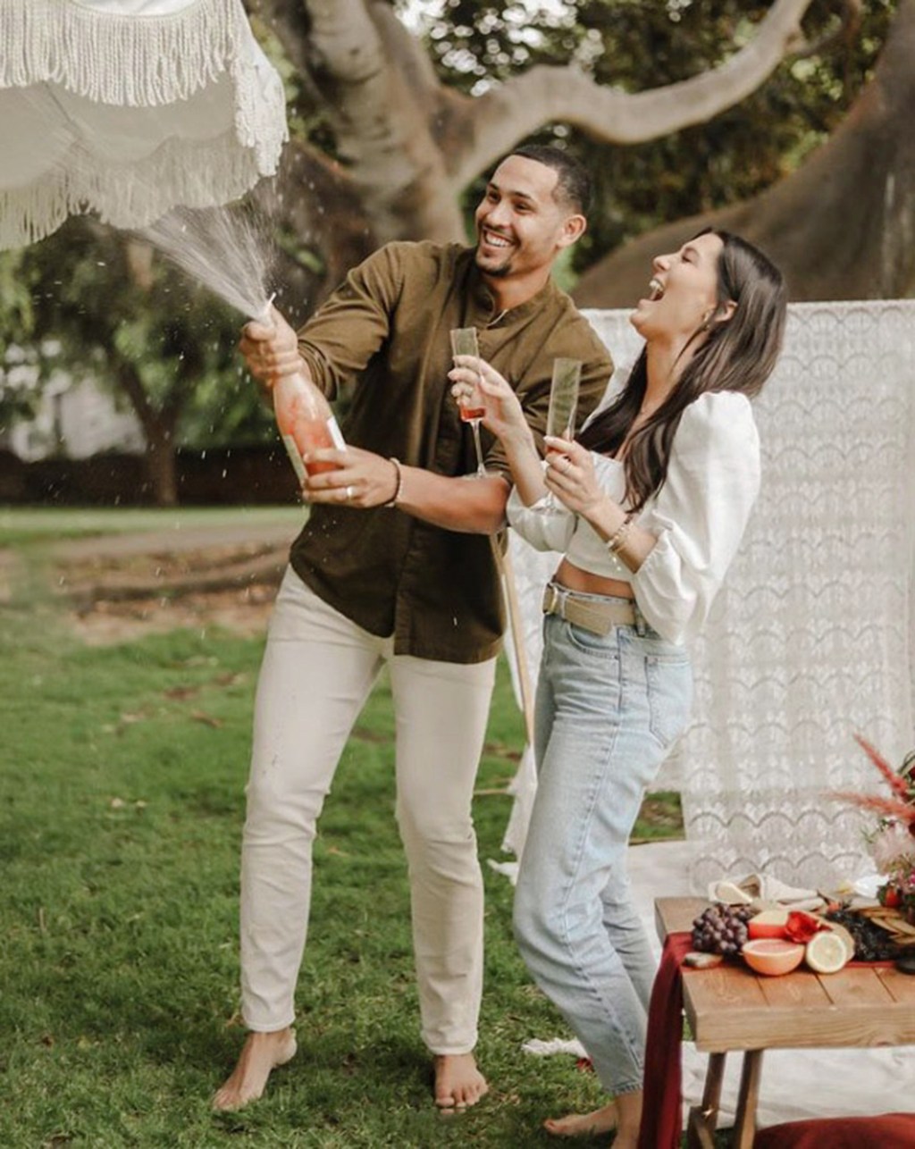 Becca Kufrin and Thomas Jacobs popping champagne.