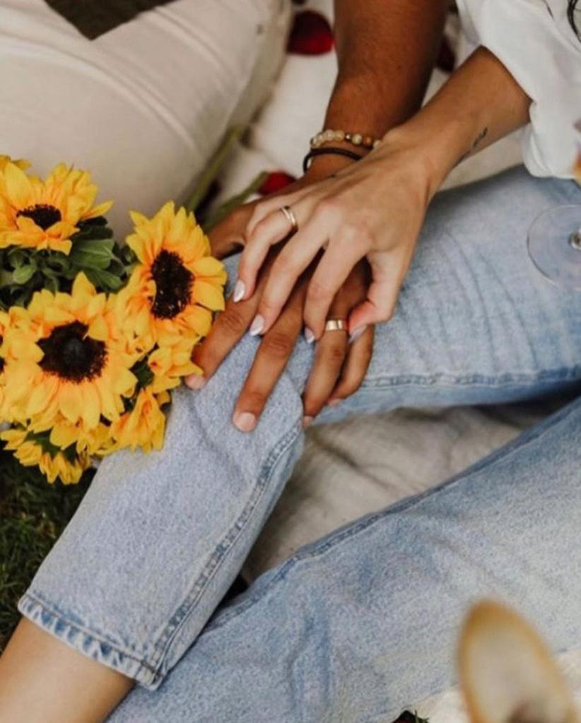 A close-up of Becca Kufrin and Thomas Jacobs holding hands.